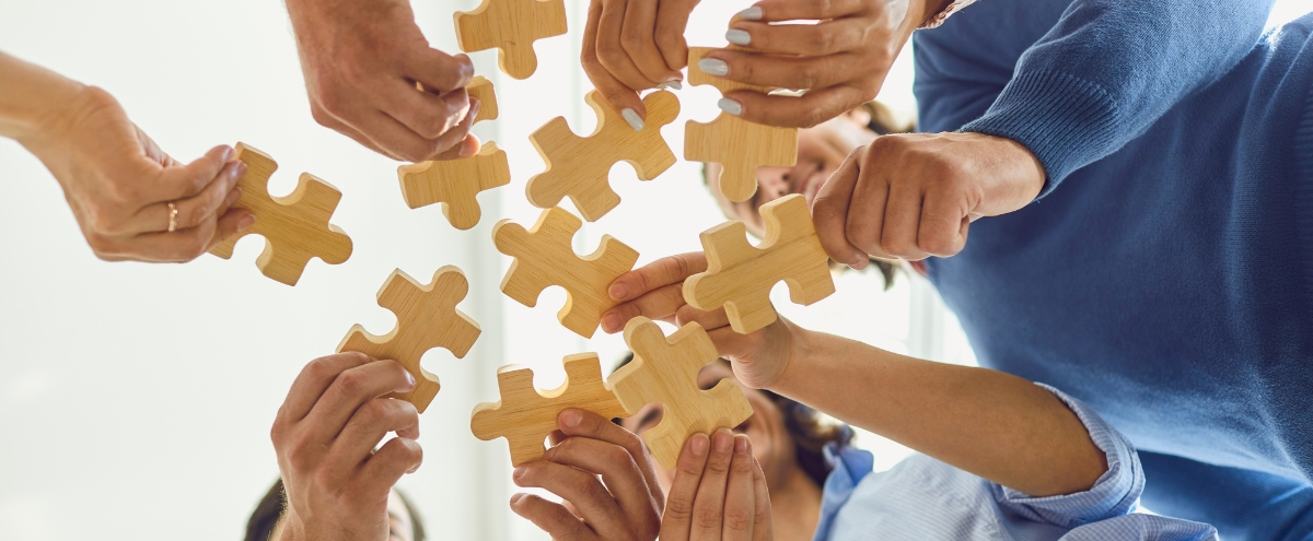 Hands fitting puzzle pieces together
